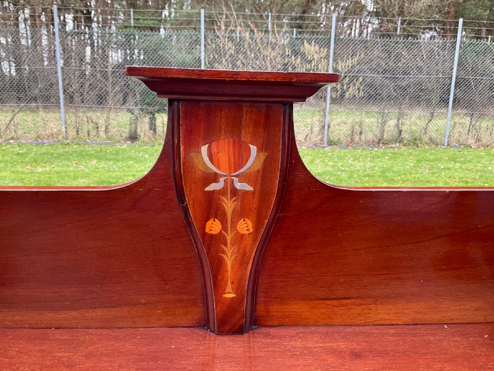An Art Nouveau mahogany glazed bookcase featuring two glass panel doors with stylised botanical wood inlay and a raised gallery top. View X