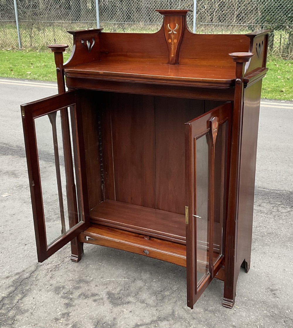An Art Nouveau mahogany glazed bookcase featuring two glass panel doors with stylised botanical wood inlay and a raised gallery top. View XIV