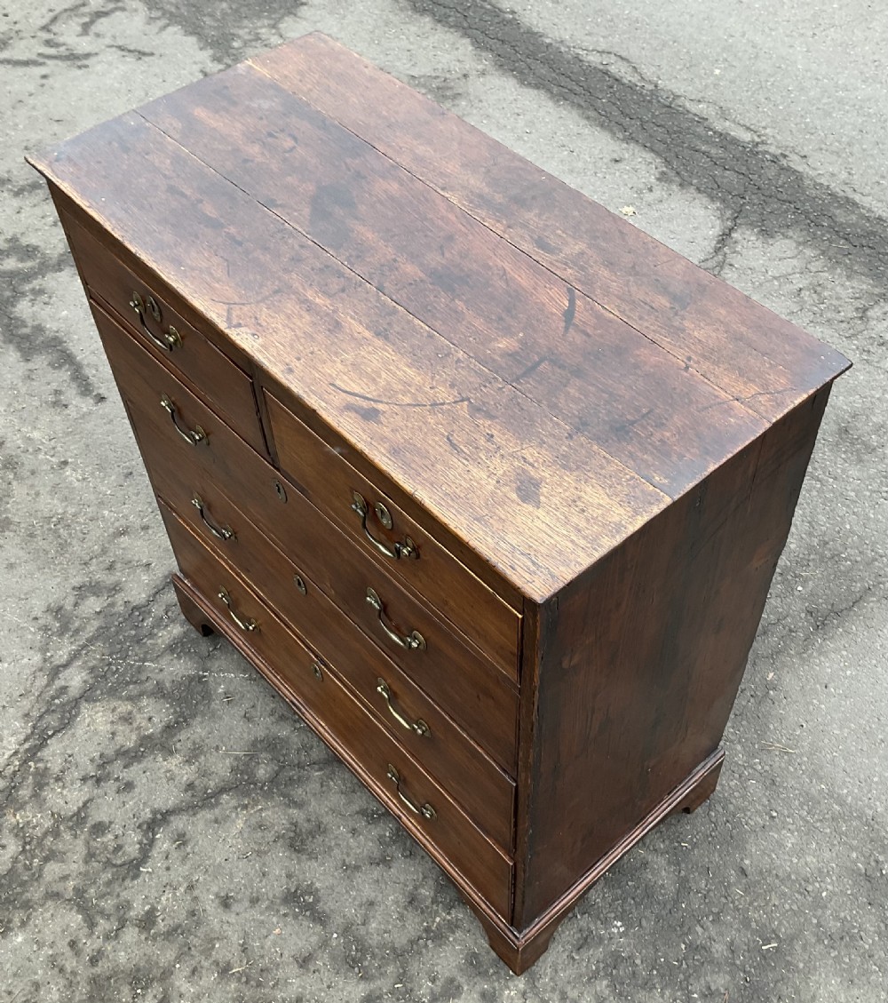 A Georgian oak chest featuring two short drawers over three long graduated drawers with brass swan-neck handles and bracket feet. View II