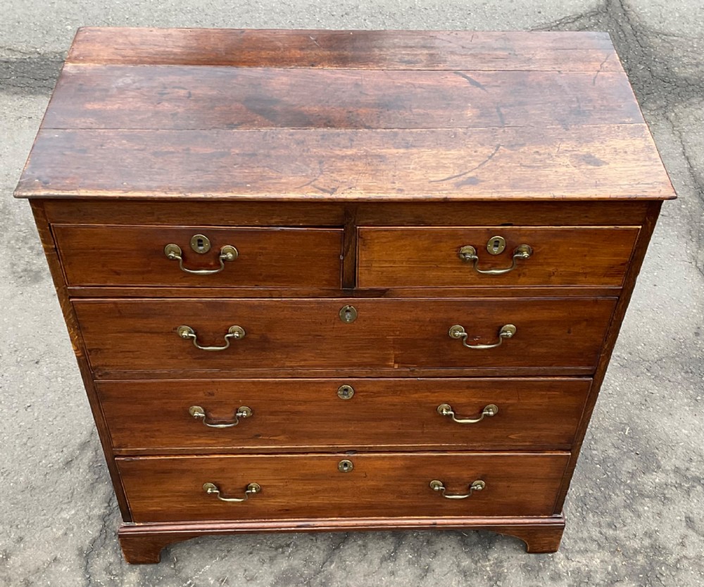 A Georgian oak chest featuring two short drawers over three long graduated drawers with brass swan-neck handles and bracket feet. View IV
