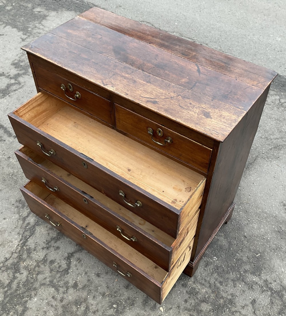 A Georgian oak chest featuring two short drawers over three long graduated drawers with brass swan-neck handles and bracket feet. View IX