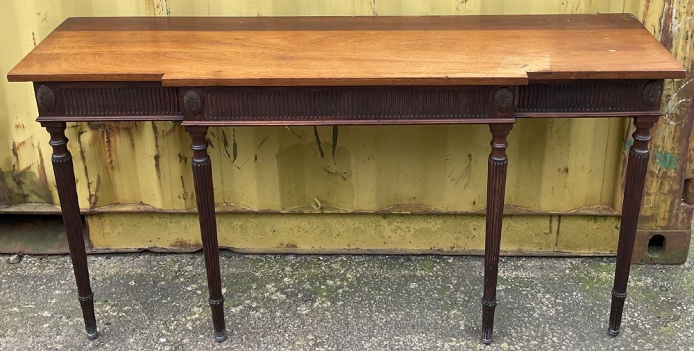 A Georgian style mahogany breakfront console table featuring a projecting centre top, fluted frieze, carved rosette corner medallions, and four tapered reeded legs.