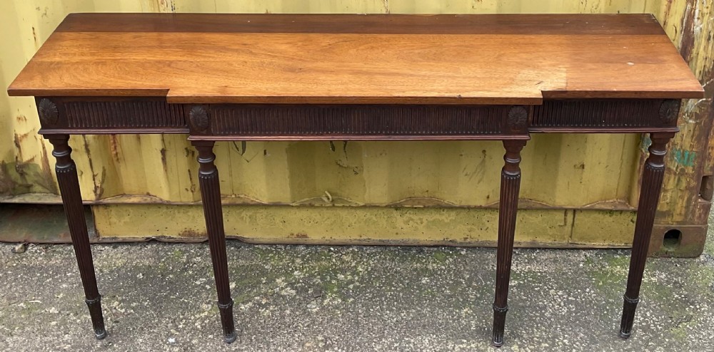 A Georgian style mahogany breakfront console table featuring a projecting centre top, fluted frieze, carved rosette corner medallions, and four tapered reeded legs. View II