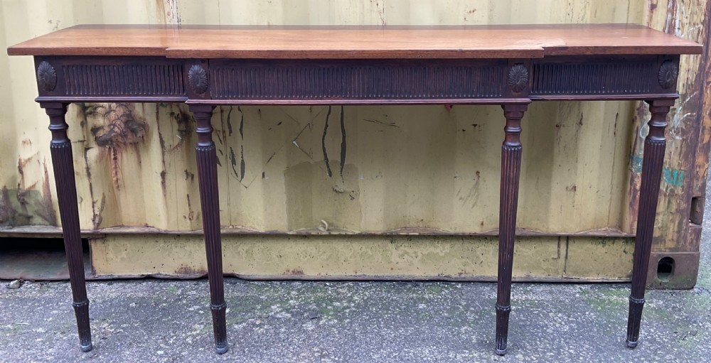 A Georgian style mahogany breakfront console table featuring a projecting centre top, fluted frieze, carved rosette corner medallions, and four tapered reeded legs. View III