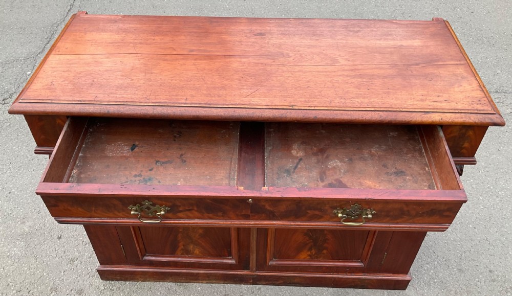 A Victorian mahogany two-door sideboard featuring flame mahogany door panels, carved scroll details, side corbels, and brass drawer handles. View V