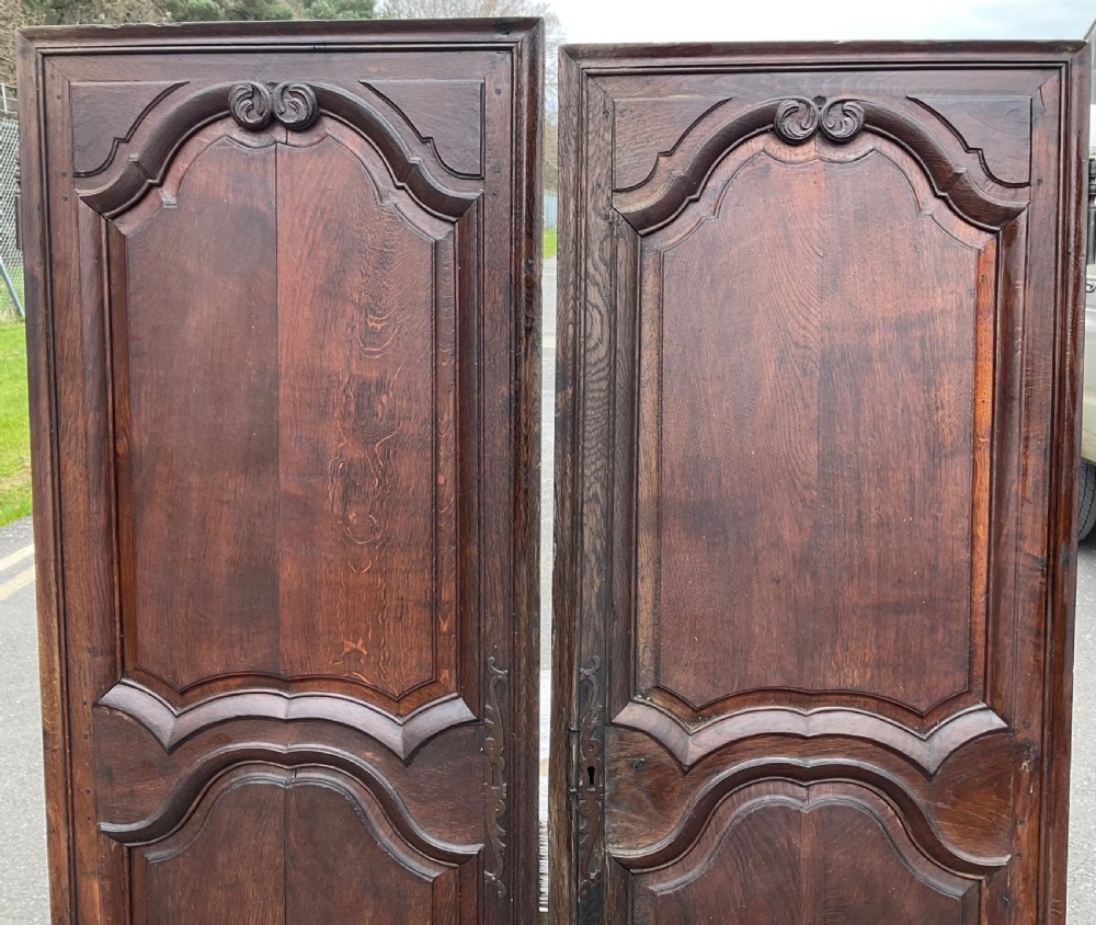 A pair of dark brown antique walnut armoire doors featuring shaped fielded panels and carved top scroll details. View III