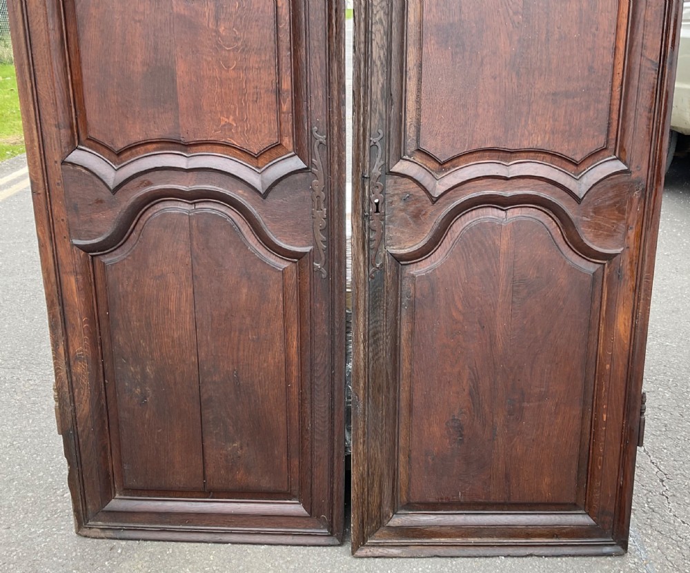 A pair of dark brown antique walnut armoire doors featuring shaped fielded panels and carved top scroll details. View IV