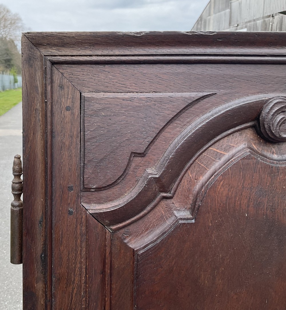 A pair of dark brown antique walnut armoire doors featuring shaped fielded panels and carved top scroll details. View V