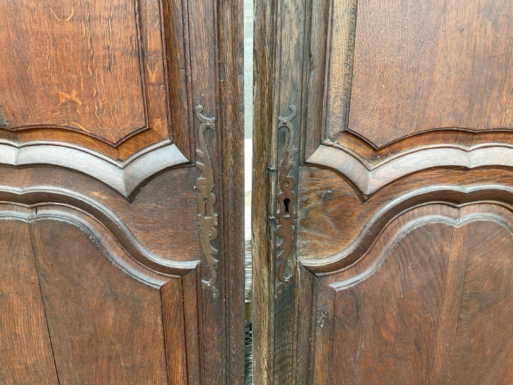 A pair of dark brown antique walnut armoire doors featuring shaped fielded panels and carved top scroll details. View VI