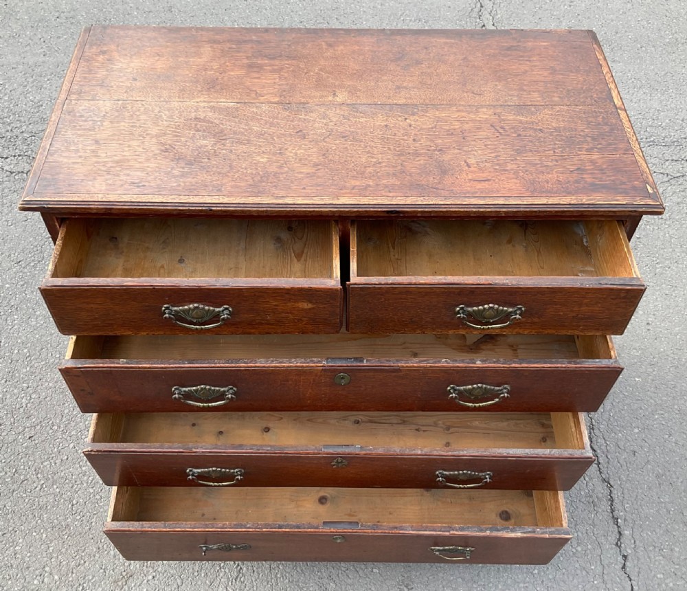 A Georgian oak chest of drawers featuring two short drawers over three long drawers with brass drop handles and bracket feet. View VIII