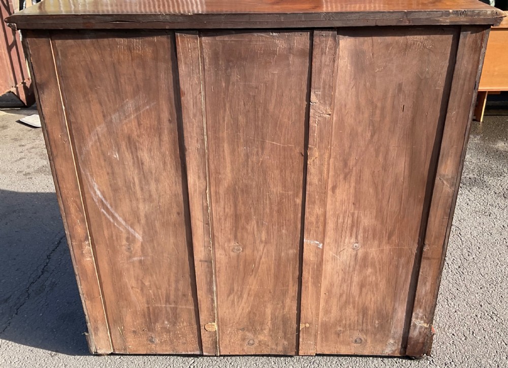 A Victorian burr walnut chest of drawers featuring a two-over-three drawer layout, decorative brass drop handles, and a solid plinth base. View XII