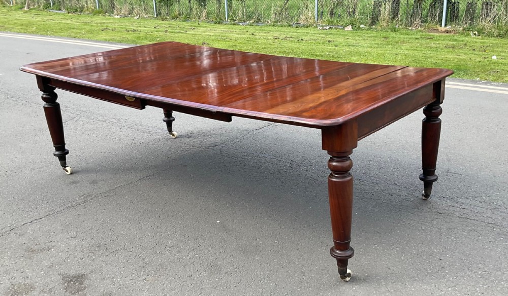 A large William IV mahogany extending dining table with turned tapered legs resting on brass and ceramic castors. View IV