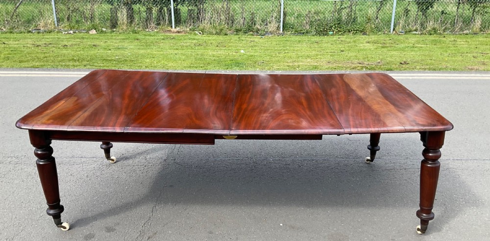 A large William IV mahogany extending dining table with turned tapered legs resting on brass and ceramic castors. View VIII