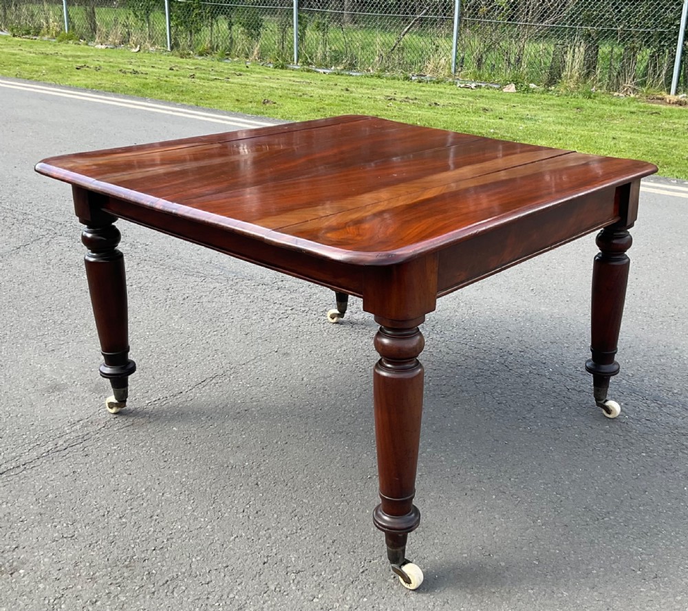 A large William IV mahogany extending dining table with turned tapered legs resting on brass and ceramic castors. View XIII