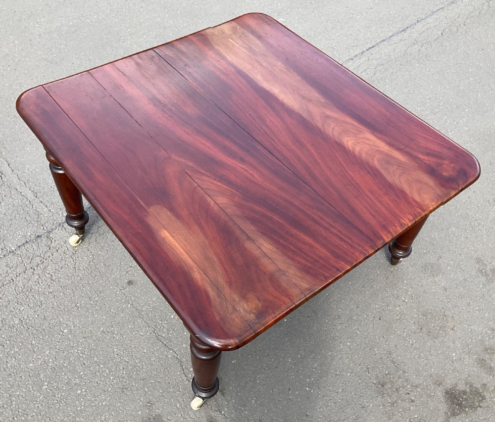 A large William IV mahogany extending dining table with turned tapered legs resting on brass and ceramic castors. View XIV