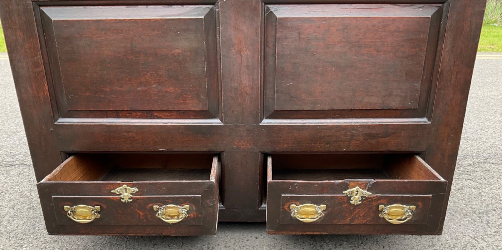 An antique dark oak mule chest featuring two raised front panels above two short drawers with brass handles and keyholes. View IX