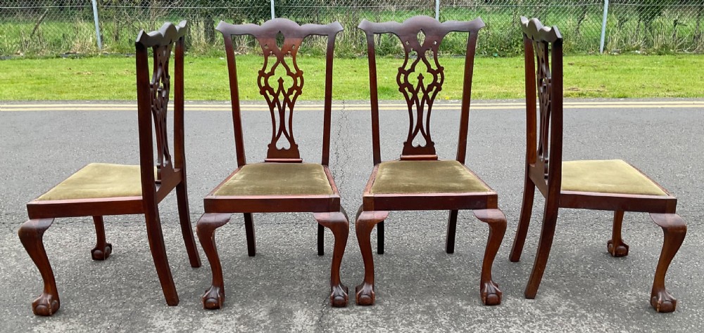 A set of four Chippendale style mahogany dining chairs with carved pierced back splats, olive fabric drop-in seats, and cabriole front legs ending in ball and claw feet. View IV