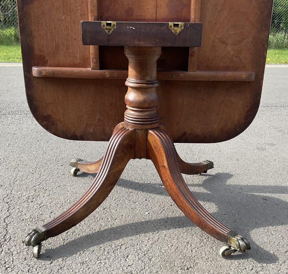 A Georgian mahogany tilt-top breakfast table featuring a crossbanded border, fine inlay stringing, and reeded quadruped legs ending in brass claw feet with castors. View VI