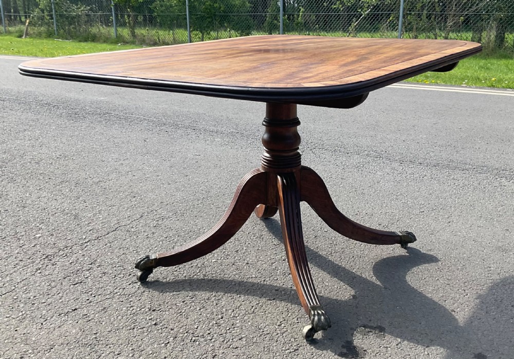 A Georgian mahogany tilt-top breakfast table featuring a crossbanded border, fine inlay stringing, and reeded quadruped legs ending in brass claw feet with castors. View VIII