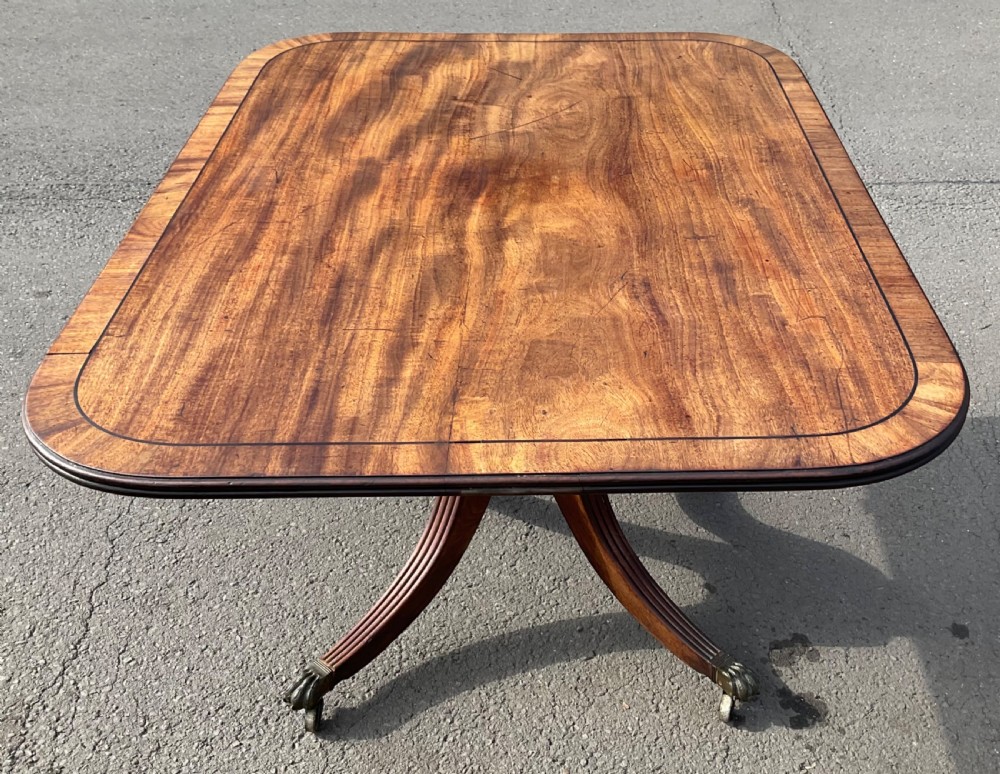 A Georgian mahogany tilt-top breakfast table featuring a crossbanded border, fine inlay stringing, and reeded quadruped legs ending in brass claw feet with castors. View IX
