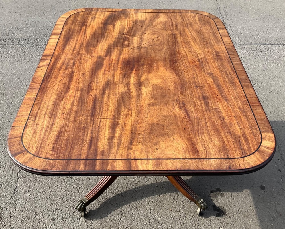 A Georgian mahogany tilt-top breakfast table featuring a crossbanded border, fine inlay stringing, and reeded quadruped legs ending in brass claw feet with castors. View XI