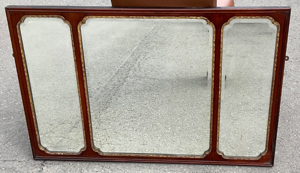 A horizontal walnut framed overmantel mirror featuring three separate glass panels with gilded inner slip borders.