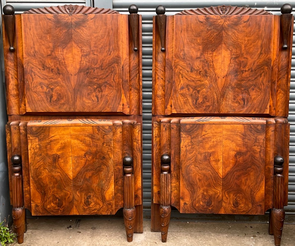 A pair of Art Deco burr walnut single bed frames featuring carved fan crests and geometric posts.