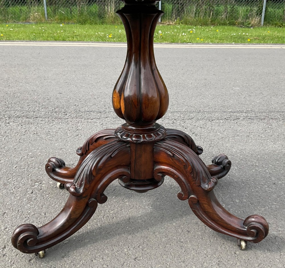 A Victorian rosewood fold-over card table featuring a shaped carved apron, bulbous turned pedestal, and four scrolled legs with brass castors. View VII