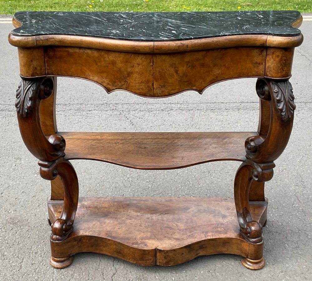 A Victorian serpentine-front console table crafted from figured wood with a dark green marble top and carved scroll legs. View II