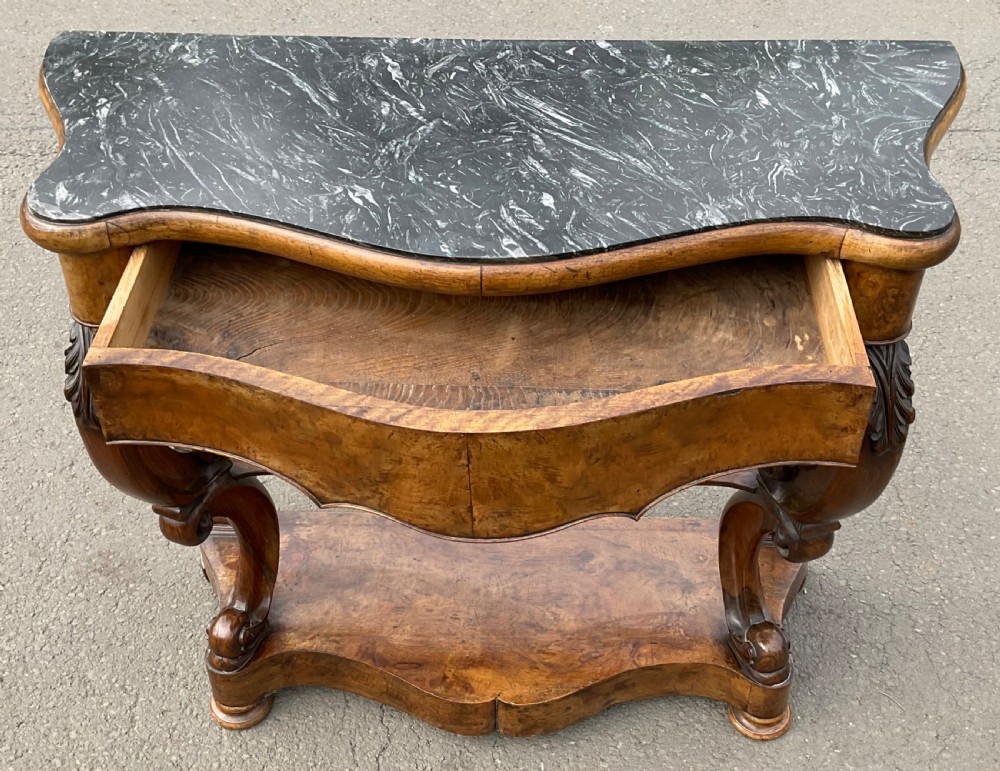 A Victorian serpentine-front console table crafted from figured wood with a dark green marble top and carved scroll legs. View VII