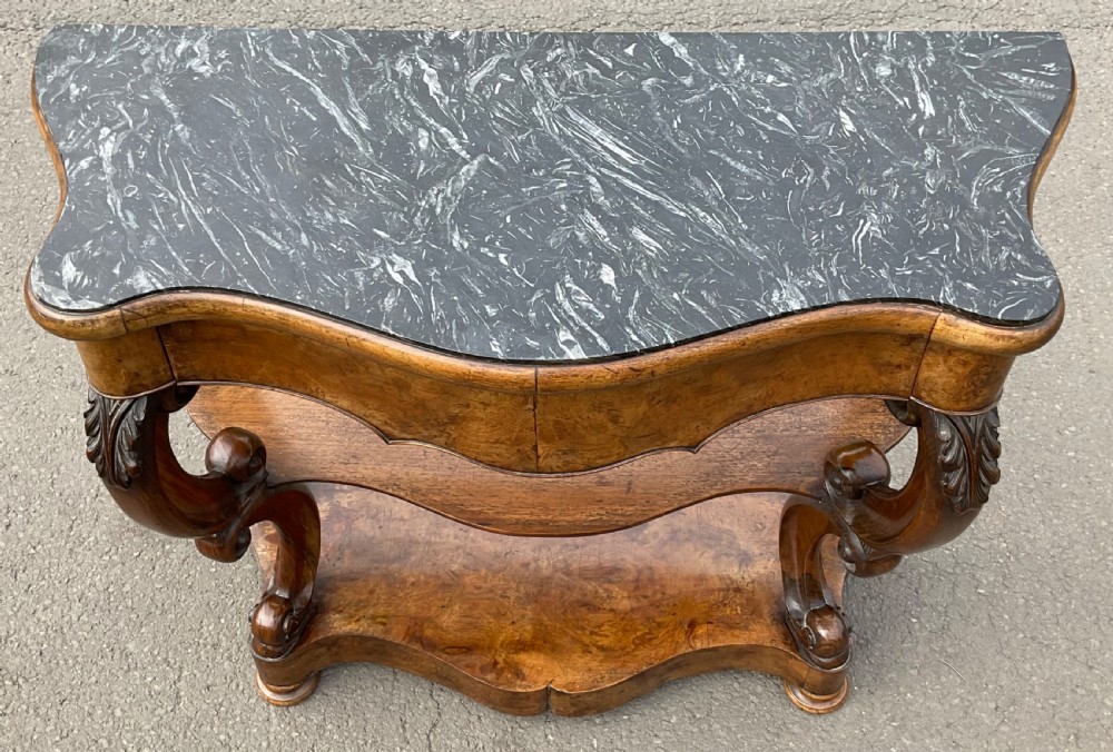 A Victorian serpentine-front console table crafted from figured wood with a dark green marble top and carved scroll legs. View IX