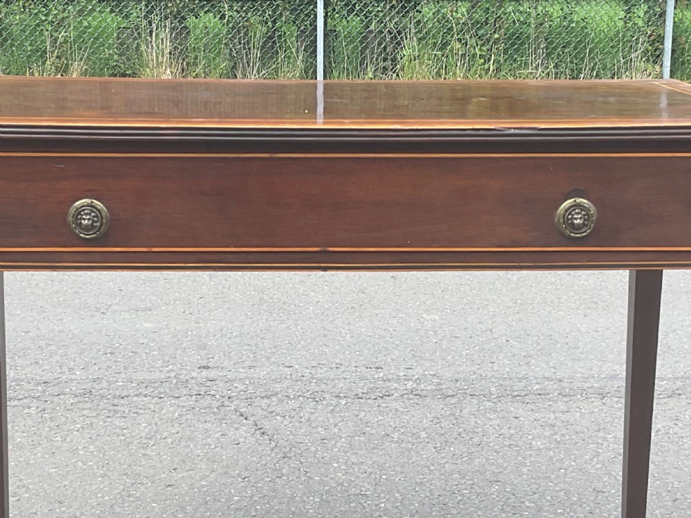 A Georgian mahogany writing table featuring boxwood string inlay on the rectangular top, a single drawer with twin brass ring handles, and square tapered legs on brass castors. View III