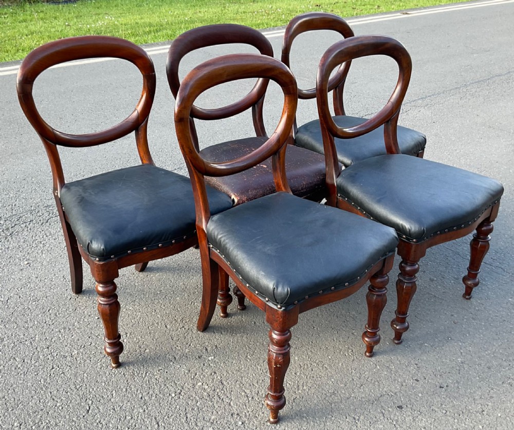 A set of five Victorian mahogany dining chairs featuring rounded balloon backrests, dark leather upholstered seats, and turned front legs. View II
