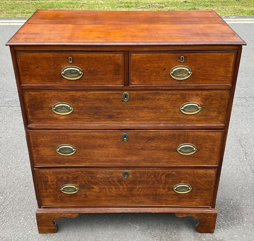 A Georgian oak chest of drawers featuring a two-over-three drawer configuration with oval brass drop handles and bracket feet. View III