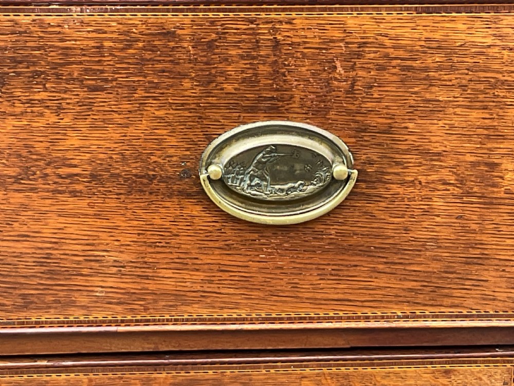 A Georgian oak chest of drawers featuring a two-over-three drawer configuration with oval brass drop handles and bracket feet. View VI