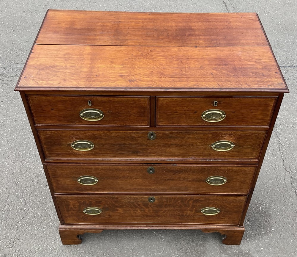 A Georgian oak chest of drawers featuring a two-over-three drawer configuration with oval brass drop handles and bracket feet. View VIII