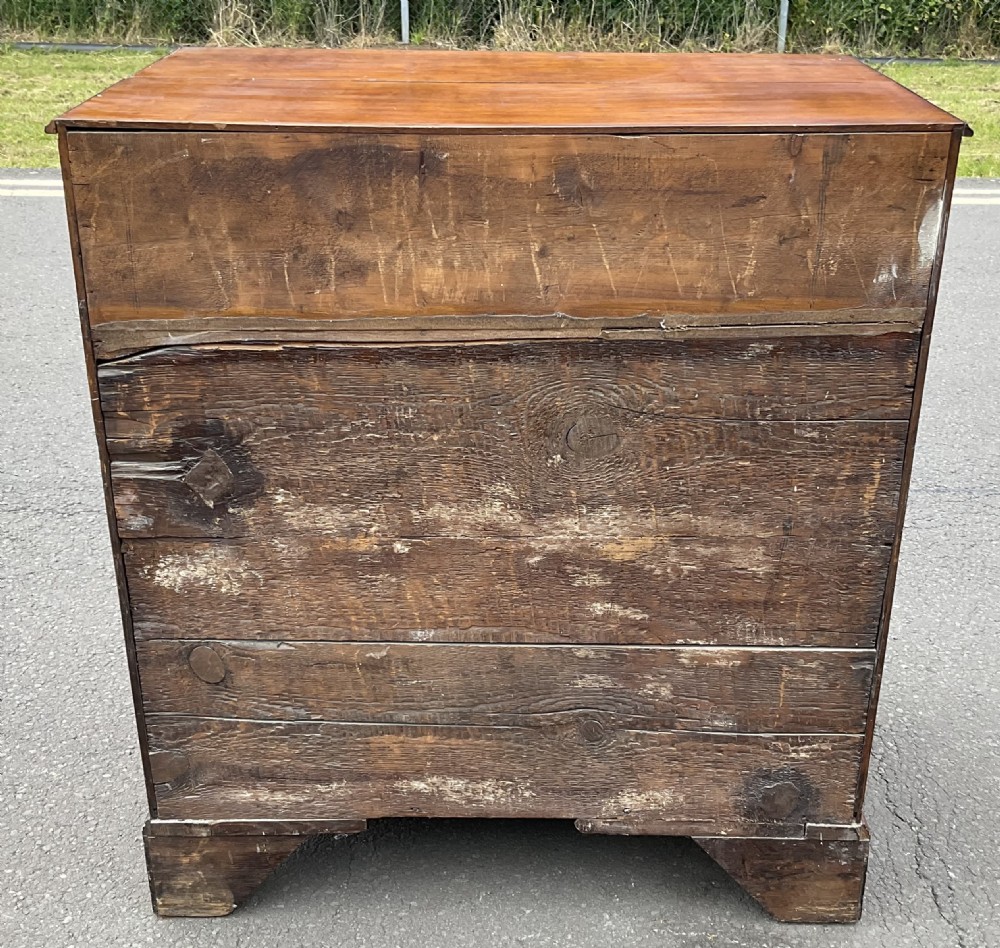 A Georgian oak chest of drawers featuring a two-over-three drawer configuration with oval brass drop handles and bracket feet. View XIII