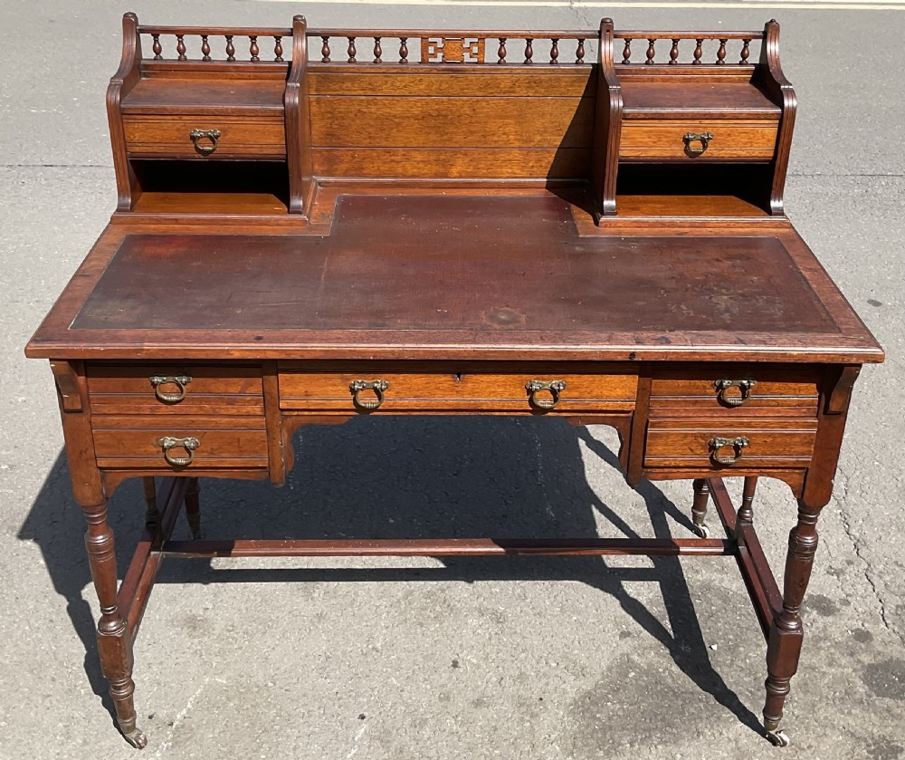 An Edwardian walnut kneehole writing desk with a leather inset top, brass ring handles, turned legs, and a raised drawer gallery. View II