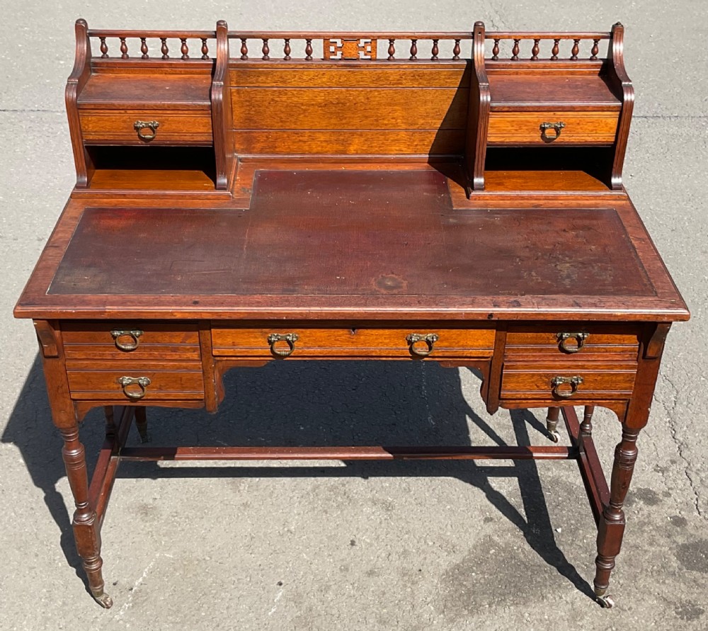 An Edwardian walnut kneehole writing desk with a leather inset top, brass ring handles, turned legs, and a raised drawer gallery. View III