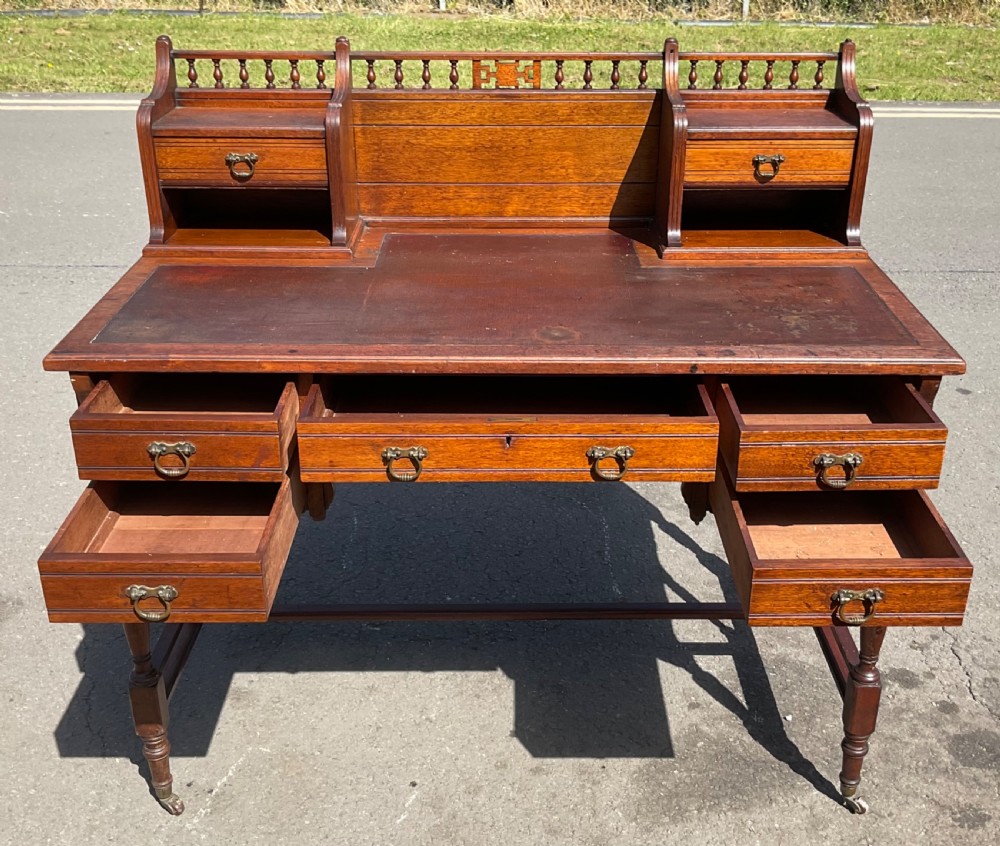 An Edwardian walnut kneehole writing desk with a leather inset top, brass ring handles, turned legs, and a raised drawer gallery. View VIII