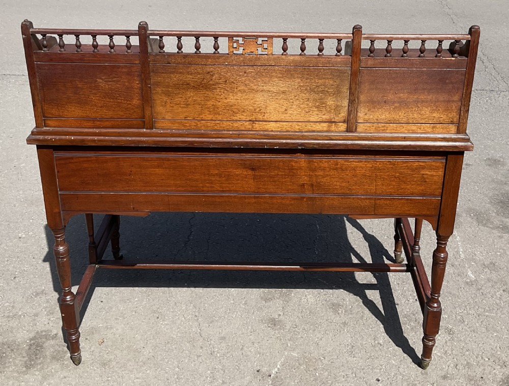 An Edwardian walnut kneehole writing desk with a leather inset top, brass ring handles, turned legs, and a raised drawer gallery. View XI