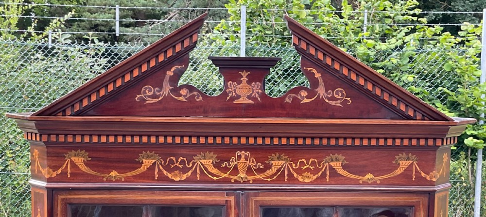An Edwardian inlaid mahogany standing corner cabinet featuring a broken pediment, astragal glazed upper doors, and marquetry inlaid lower panels. View VI