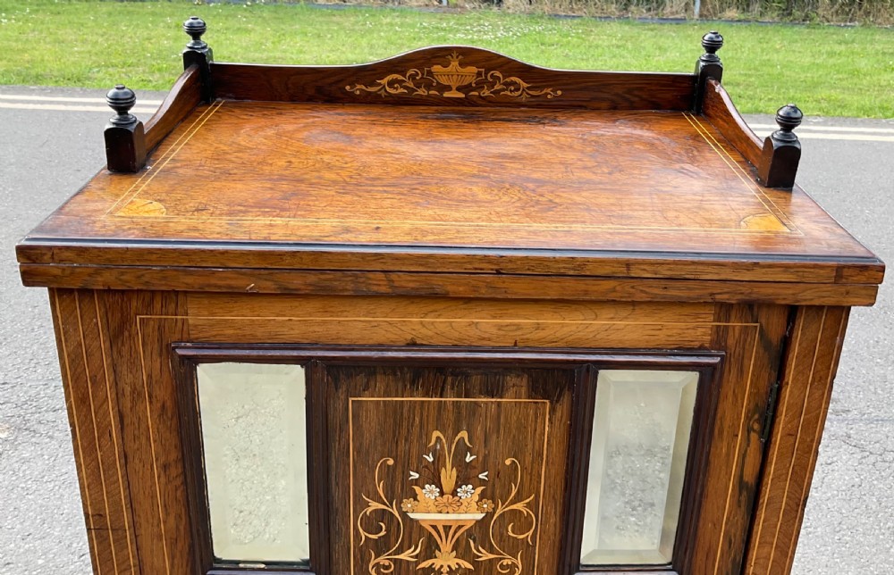 An Edwardian inlaid rosewood music cabinet featuring marquetry urn motifs, mirrored panels, a glazed lower door, and turned corner finials. View III
