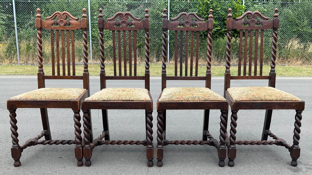A set of four dark oak Jacobean style dining chairs featuring barley twist uprights, carved crest rails, and tapestry fabric seats. View II