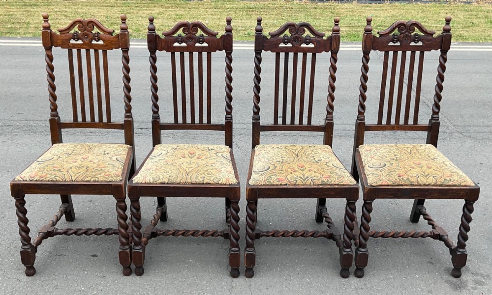 A set of four dark oak Jacobean style dining chairs featuring barley twist uprights, carved crest rails, and tapestry fabric seats. View III
