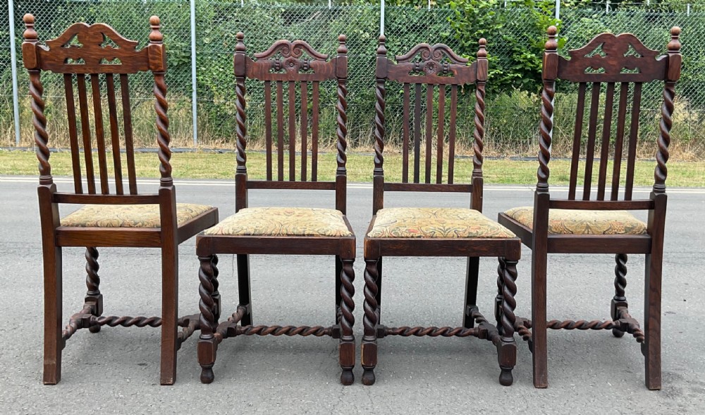 A set of four dark oak Jacobean style dining chairs featuring barley twist uprights, carved crest rails, and tapestry fabric seats. View IV