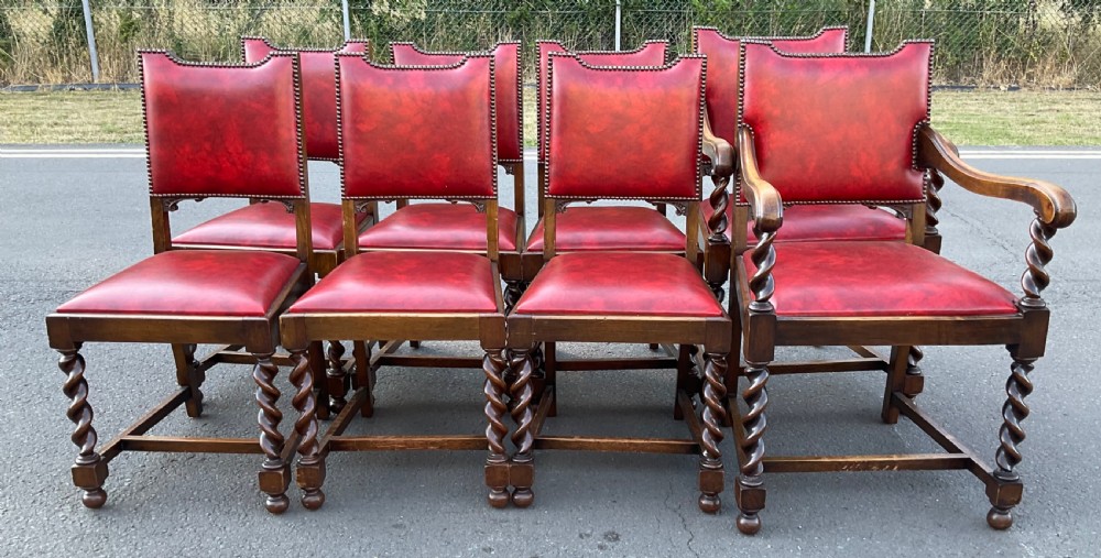 A set of eight oak dining chairs featuring red leather upholstery with brass stud detailing and spiral barley twist legs. View II