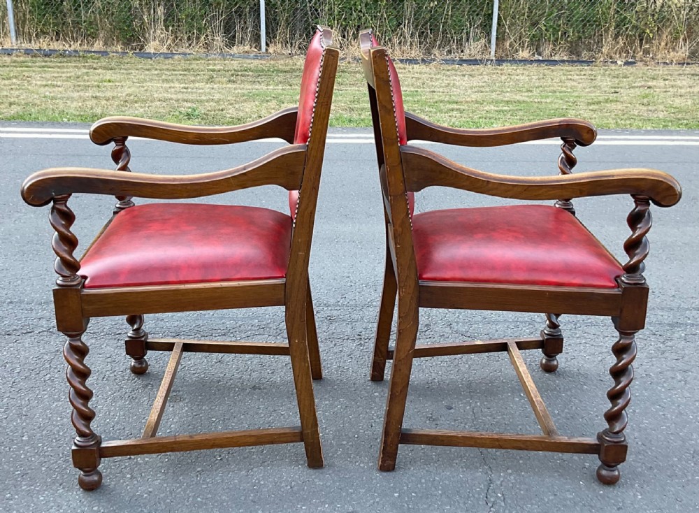 A set of eight oak dining chairs featuring red leather upholstery with brass stud detailing and spiral barley twist legs. View VI