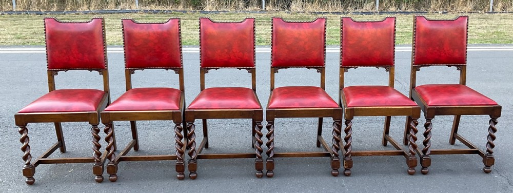 A set of eight oak dining chairs featuring red leather upholstery with brass stud detailing and spiral barley twist legs. View IX