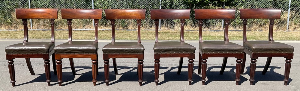 A set of six William IV mahogany dining chairs featuring curved top rails, reeded front legs, and dark green leather upholstered seats. View II